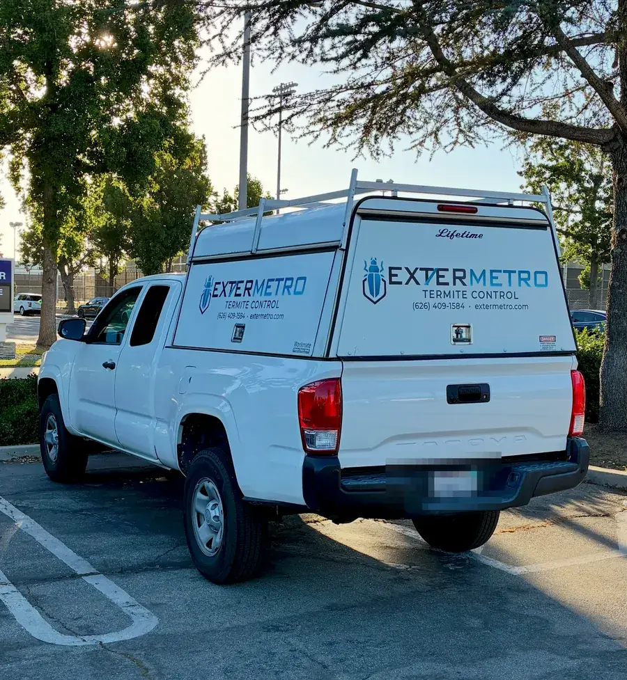 The white ExterMetro work truck with the company logo on its camper shell, parked between jobs in the San Gabriel Valley