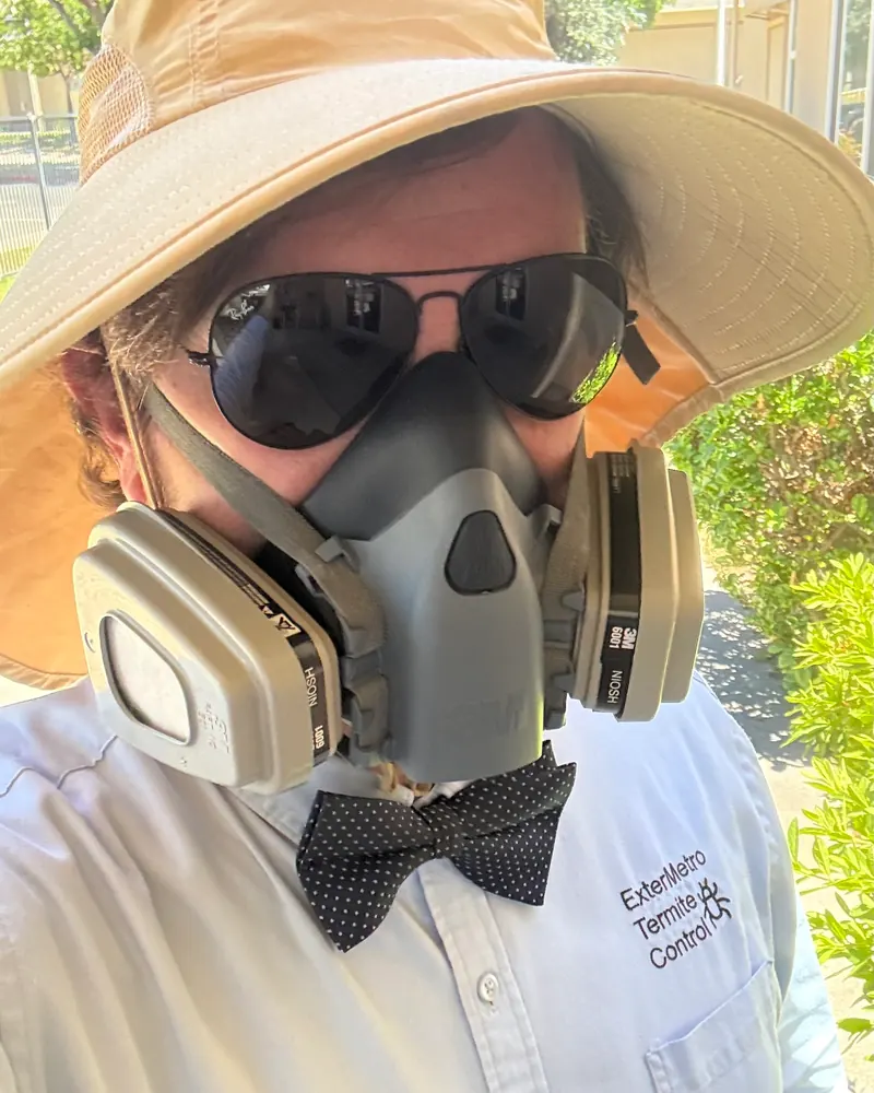 The ExterMetro owner suited up for a treatment day in respirator, sun hat, and his signature bow tie